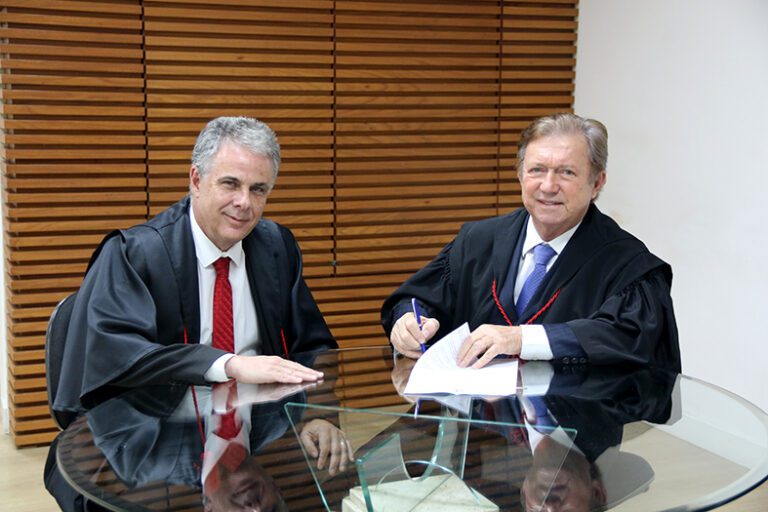 O presidente do TJES, desembargador Fabio Clem, e o desembargador Jorge Henrique dos Santos assinando um documento.