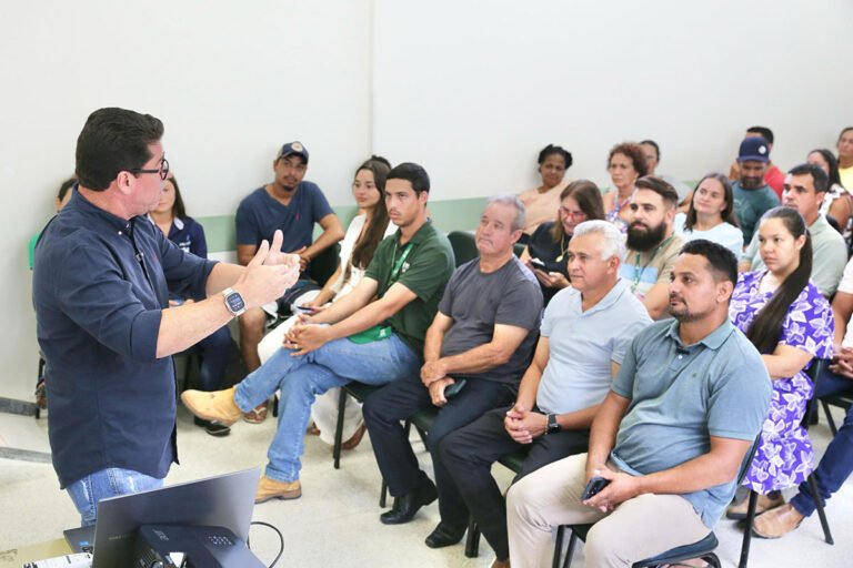 homem em pé ao microfone e pessoas sentadas