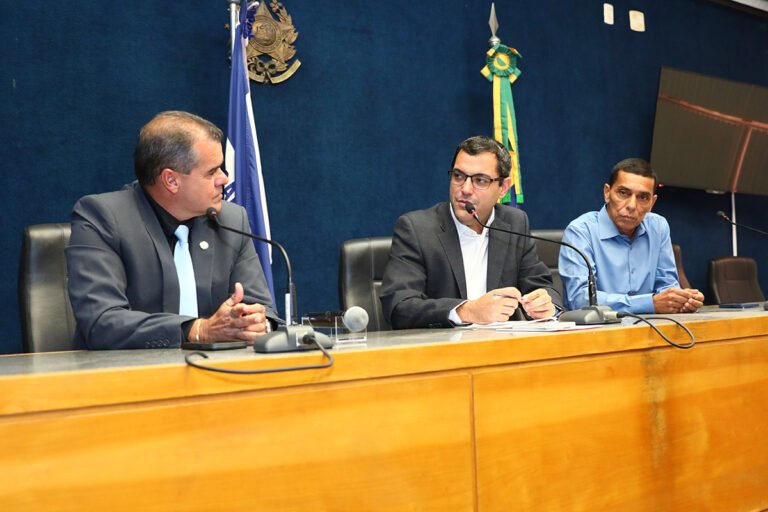 Deputados Fábio Duarte, Dr. Bruno Resende e Zé Preto sentados atrás de mesa durante reunião 